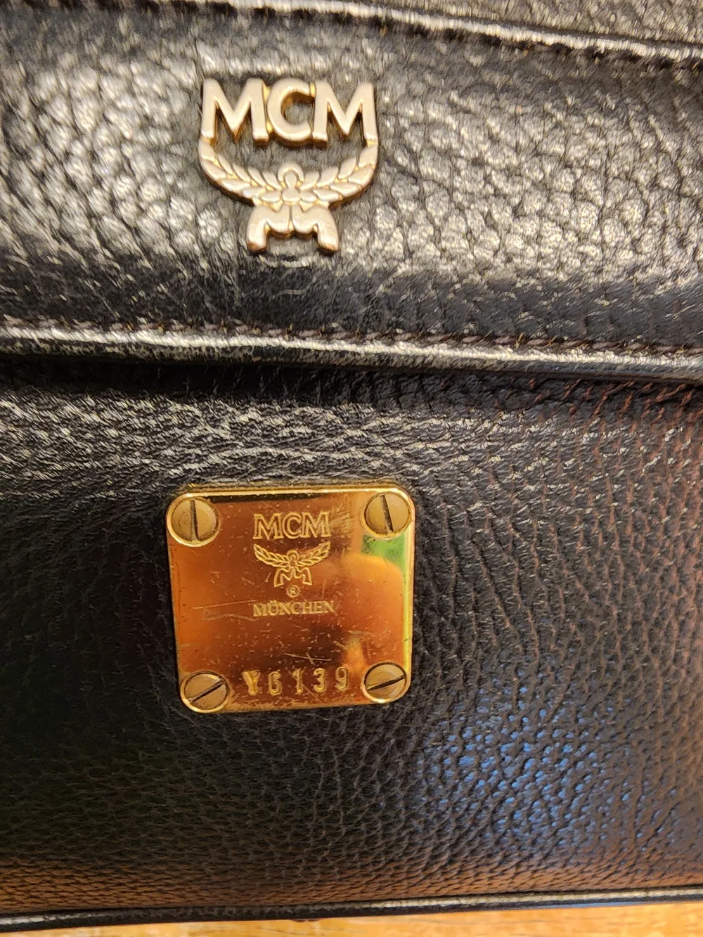 vintage MCM black pebbled leather studded crossbody bag featuring a front plaque
